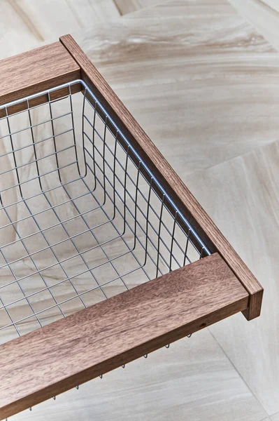 Storage organization. Metal mesh basket in wooden drawer in food storage room. Close-up