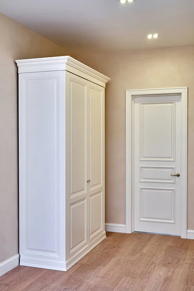 Classic wardrobe and interior door in beige interior. Classic furniture. Furniture manufacture