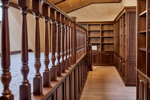 Home library. Wooden bookcase with empty shelves and a wooden balustrade placed in home library in house