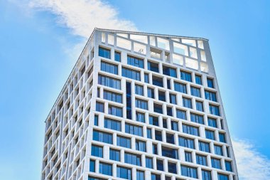 Şehirde güneşli bir günde bulutsuz mavi gökyüzüne karşı geometrik tasarımı olan çağdaş yüksek şehir binası