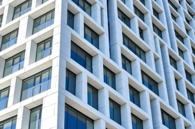 Çağdaş geometrik paneller ve cam pencereler tasarımı ile modern çok katlı binanın alçak açılı köşe manzarası