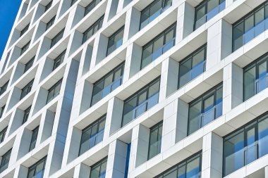 Çağdaş geometrik paneller ve cam pencereler tasarımı ile modern çok katlı binanın alçak açılı köşe manzarası