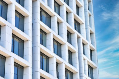 Güneşli bir günde bulutlu mavi gökyüzüne karşı geometrik tasarımı olan çağdaş yüksek şehir binası