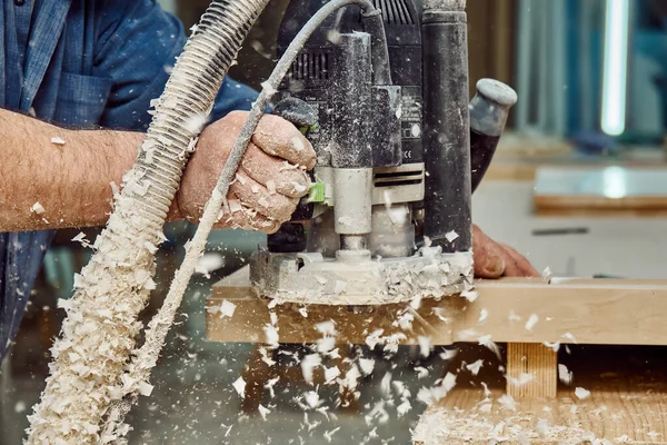 Carpenter with hand electric router machine at work. Milling process of acrylic kitchen countertop is carried out using a manual milling machine