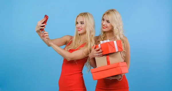 Kırmızılı kızlar bir yığın hediyeyle kendi fotoğraflarını çekerler..