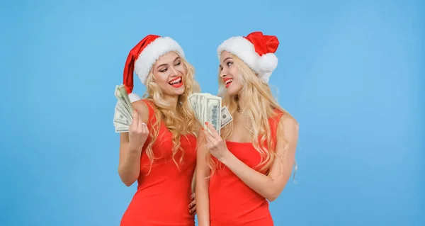 Noel Baba şapkalı ikiz kızlar nakit para içinde birbirlerini gösterirler..