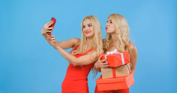 Kırmızı elbiseli kızlar hediyelerle selfie çekerler..