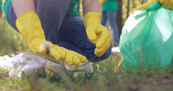 Sarı eldivenli bir adam çöp toplar..
