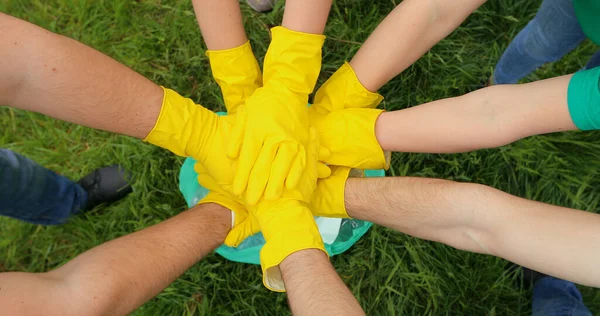 Sarı eldivenli bir ekip kollarını çerçevenin ortasında kavuşturuyor..