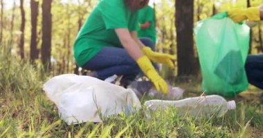 Parktaki ön planda yeşil tişörtlü gönüllüler tarafından çöp toplama.