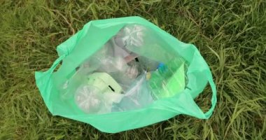 Sarı lastik eldivenli gönüllülerin el sıkışması bir torba dolusu çöpün arkasında..