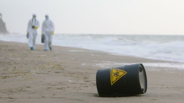 Dos Hombres Con Trajes Blancos Protección Acercan Barril Negro Con — Vídeos de Stock