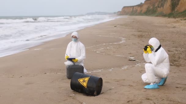 Černý Sud Známkou Biologického Nebezpečí Leží Pobřeží Dva Vědci Ochranných — Stock video