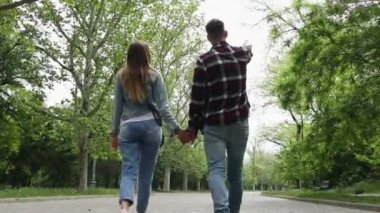 Bir bahar parkında el ele tutuşan genç bir çift sokakta yürüyor..