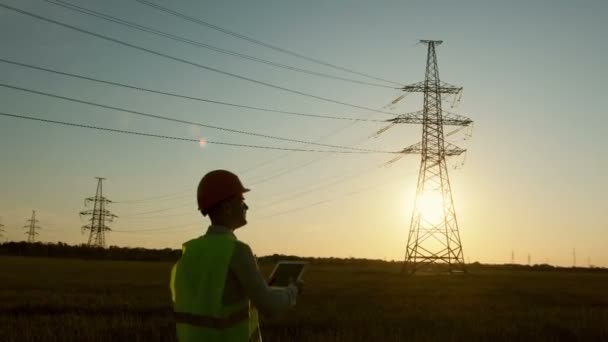 Trabalhador Energia Inspeciona Linhas Alta Tensão Pôr Sol Usando Tablet — Vídeo de Stock