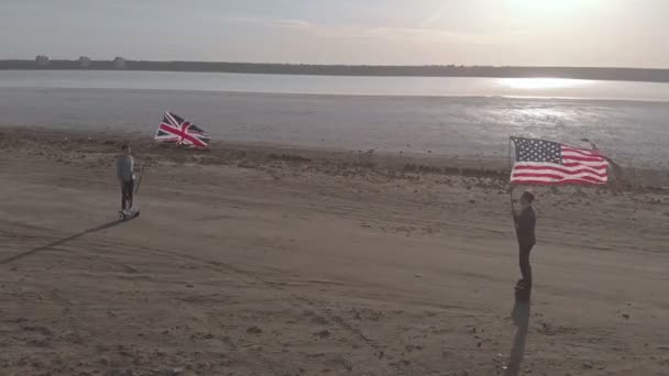 两个拿着美国和英国国旗的男人骑着陀螺滑板车互相擦肩而过 — 图库视频影像