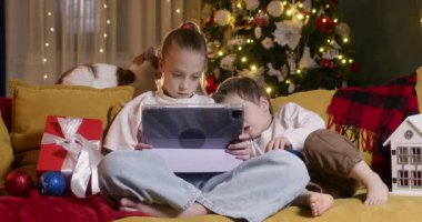 Kardeşler, modern cihazdan yansıyan görüntüleri izlerken yumuşak kucaklaşmayı paylaşırlar. Sevgili abim ve ablam birlikte ekranda video izlemenin keyfini çıkarıyorlar.