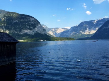 Yukarı Avusturya Hallstatt 'ta güneşli bir günde mavi gökyüzüne karşı göl ve dağların manzarası
