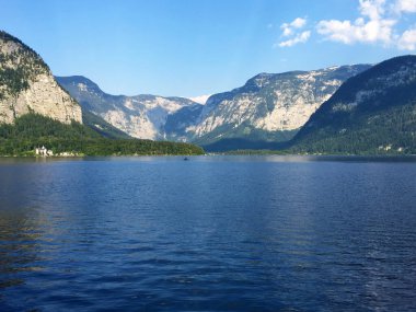 Yukarı Avusturya Hallstatt 'ta güneşli bir günde mavi gökyüzüne karşı göl ve dağların manzarası
