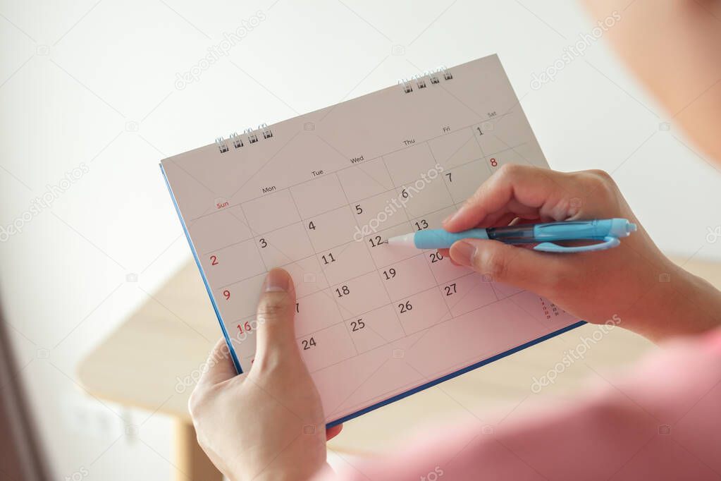 Hand with pen writing on calendar date