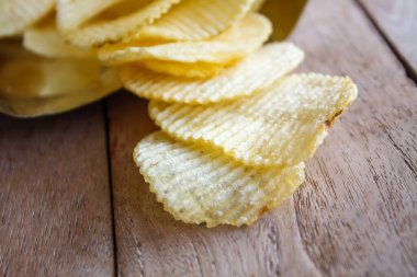 Tahta masanın üzerinde patates cipsi ile açılmış paket.