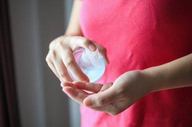 Kadın, COVID-19 Corona virüs önleme konseptini temizlemek için alkol dezenfektanı kullanıyor.