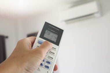 Odanın içerisindeki klimaya yönlendirilmiş uzaktan kumandalı el.