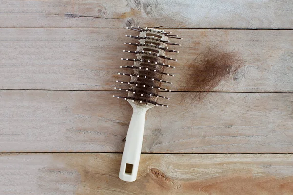 Hair loss, Close up of hairbrush with lost hair on wood table