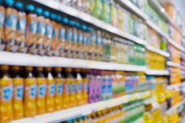 Arka planda süpermarkette raflarda duran bulanık içecekler.
