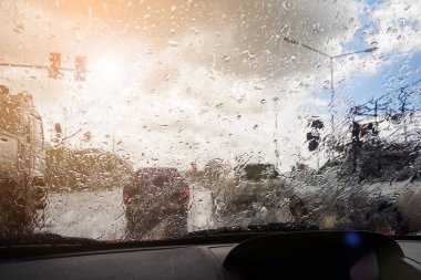 Şiddetli yağmurlu bir günde trafik vardı. Araba penceresinin içinde yol manzarası ve yağmur damlaları vardı.