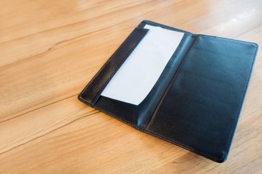 Siyah deri restoranda boş beyaz kağıt. Ahşap masada fatura klasörü.