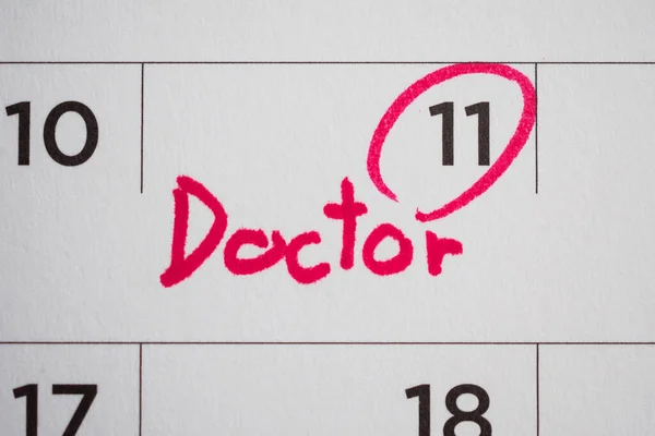 important doctor appointment schedule write on white calendar page date close up