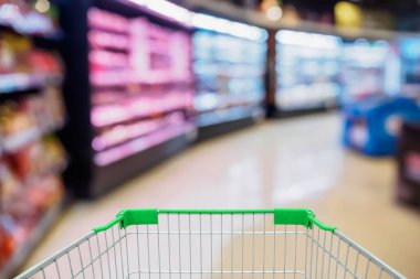 Arkaplanı bulanık alışveriş arabasıyla dolu süpermarket koridoru