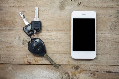Ahşap arka planda cep telefonu ve uzaktan kumandalı araba anahtarları