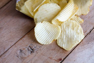 Tahta masanın üzerinde patates cipsi olan çantayı aç.