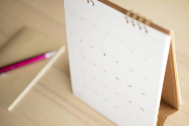 Takvim sayfası ahşap masa arkaplanını kalem ve defter iş randevusu planlama konseptiyle kapat