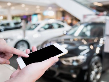 Araba galerisinde cep telefonu kullanan bir kadın. Arka plan için yeni arabalar bulanık.