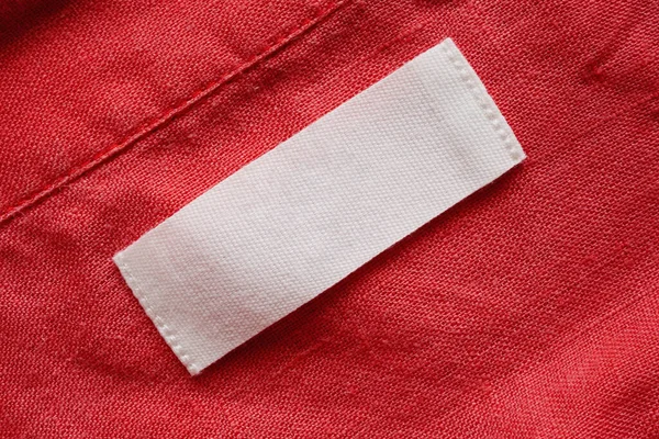 Blank clothing tag label on linen shirt fabric texture background