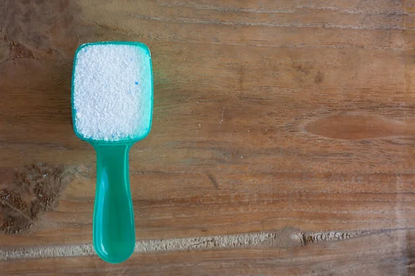 Detergent powder, detergent washing powder in the measuring spoon on wood background