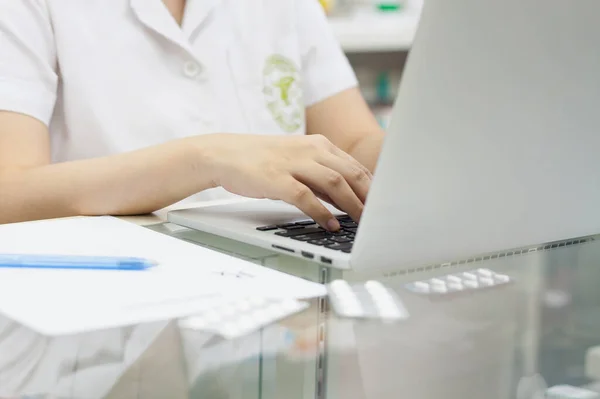 Pharmacist with laptop computer and medication in the pharmacy store