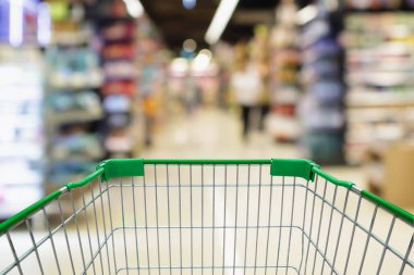 Boş yeşil alışveriş arabası arka planına sahip bulanık süpermarket koridoru