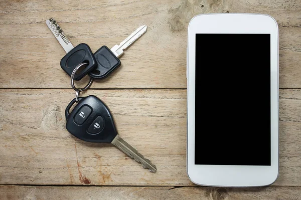 Ahşap arka planda cep telefonu ve uzaktan kumandalı araba anahtarları
