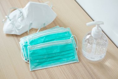 Covid-19 Coronavirus önleme konsepti için ahşap masaya alkol dezenfektanlı yüz maskesi.