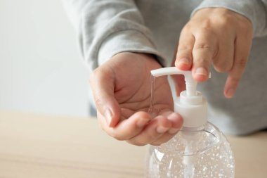 Kadın, COVID-19 Corona virüs önleme konseptini temizlemek için alkol dezenfektanı kullanıyor.