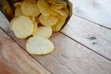 Tahta masanın üzerinde patates cipsi ile açılmış paket.