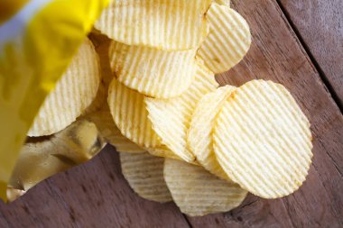 Tahta masanın üzerinde patates cipsi ile açılmış paket.