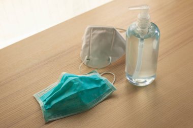 Covid-19 Coronavirus önleme konsepti için ahşap masaya alkol dezenfektanlı yüz maskesi.