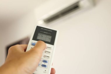 Odanın içerisindeki klimaya yönlendirilmiş uzaktan kumandalı el.