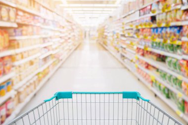 Süpermarket koridorundaki alışveriş arabası görüntüsü. Ürün rafları soyut bulanık arka plan.