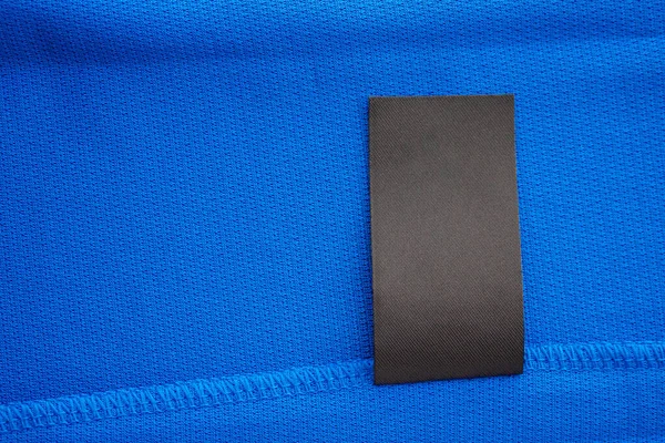 Schwarz Leere Wäschepflegeetikett Auf Blauem Jersey Polyester Sport Hemd Hintergrund — Stockfoto